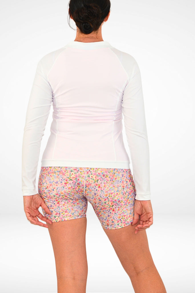 model wearing long sleeve white andavi swim rash guard and andavi swim active bike shorts in floral print