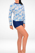 women wearing a white and blue print sun shirt with dark blue swim shorties