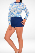 women wearing white and blue print sun shirt tied at the front and navy blue swim shorties 