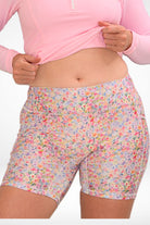 image of of a women pulling up the waist of her light pink rash guard to reveal  water colour floral bike shorts