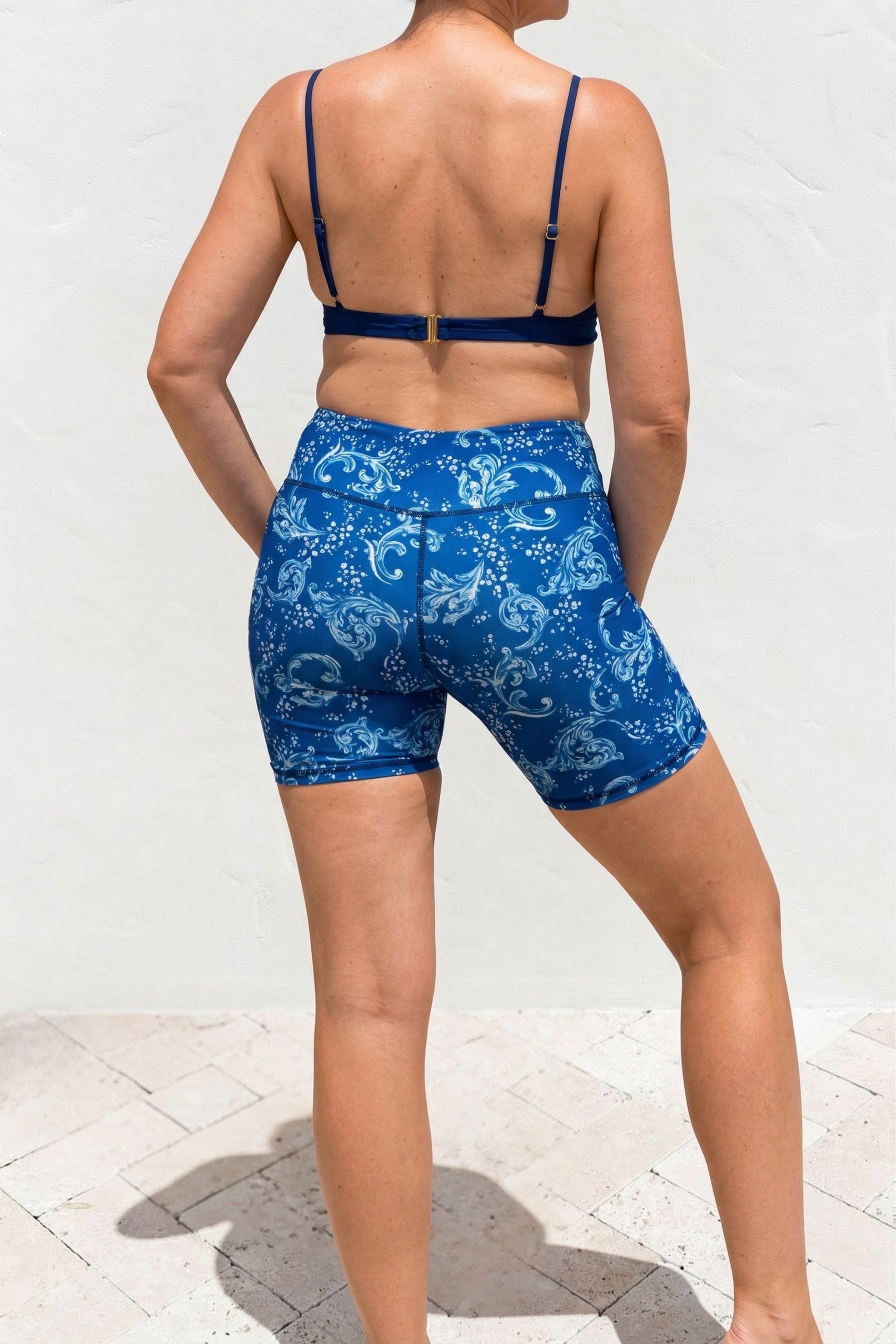 Person wearing a blue patterned swimsuit on a white background