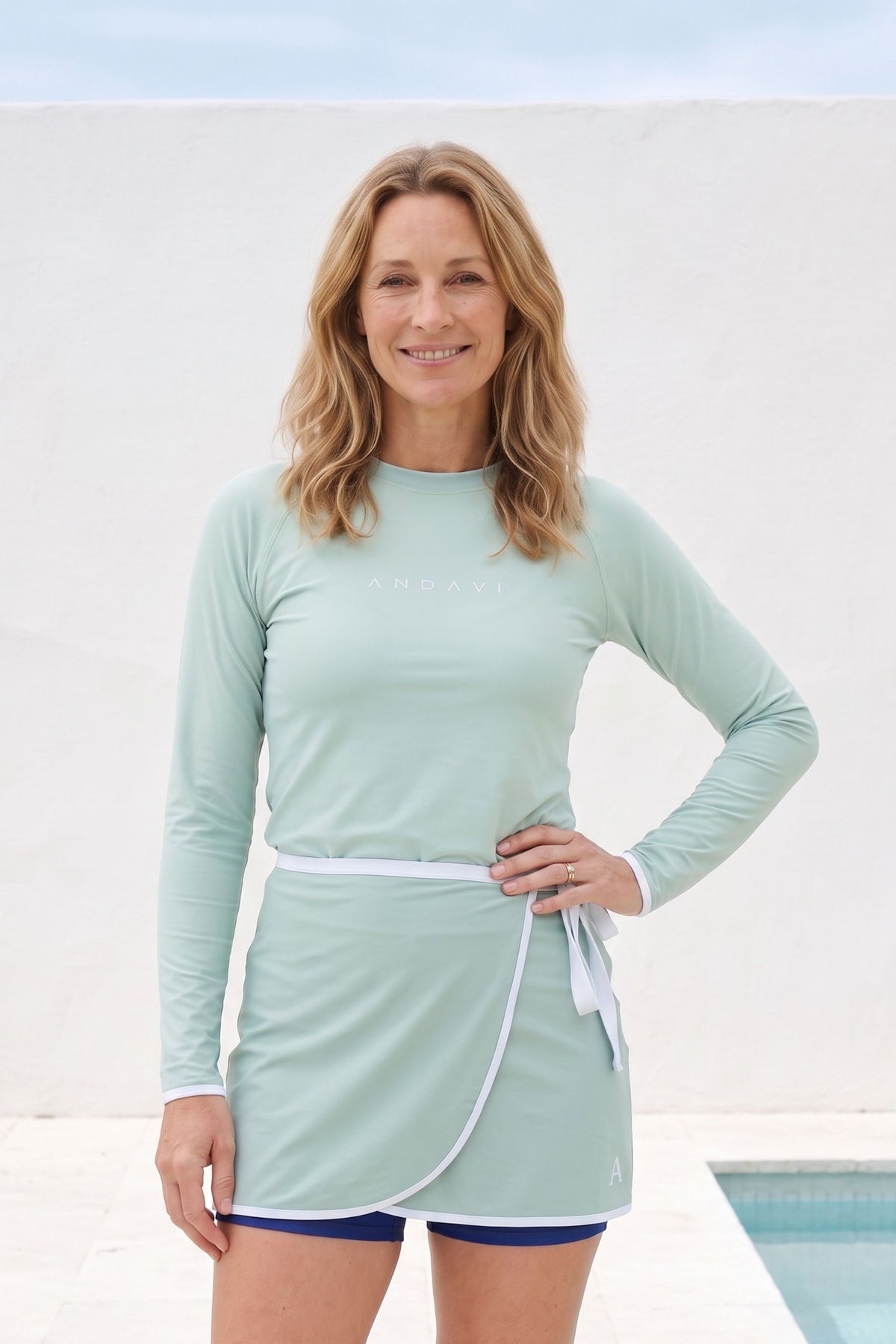 women wearing light green safe rash guard and wrap skirt and dark blue shorts underneath.