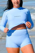 Woman wearing a blue athletic outfit with 'ANDAVI' branding on a beach.