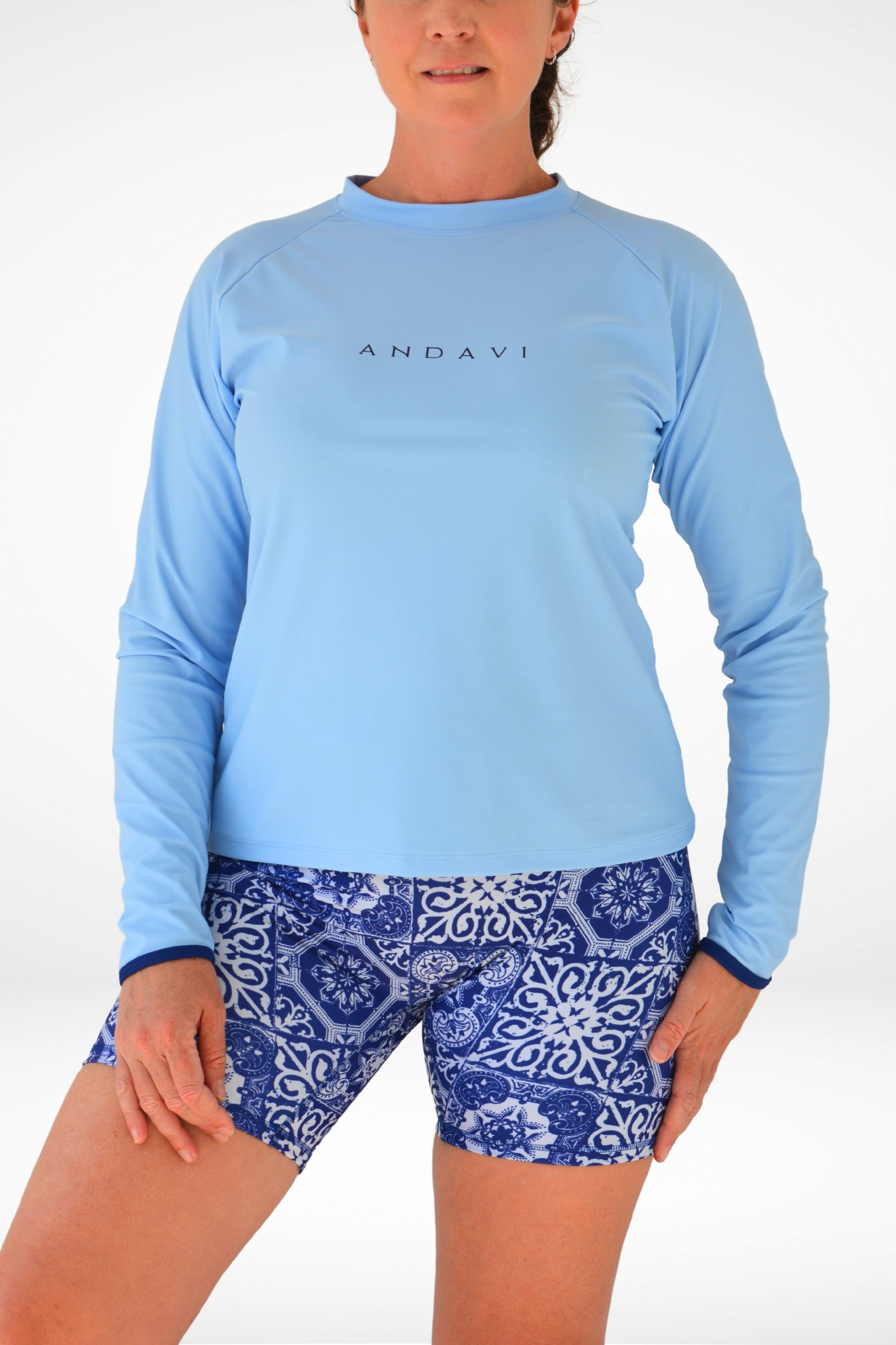 Woman wearing a blue long-sleeve shirt and patterned shorts on a white background