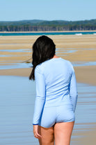 women walking on the beach wearing light blue long sleeve sun shirt rashie and matching light blue swim shorts